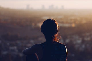 Young woman sitting looking out over city contemplating.