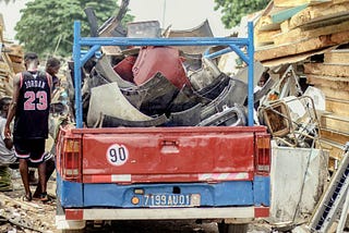 A red and blue truck with scrap metal stacked up in the back.