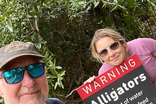 The writer and his daughter are standing by a sign warning of alligators