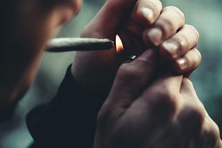 Young man lighting a marijuana joint