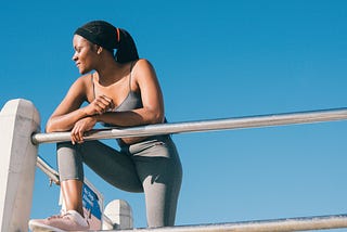 Young woman leaning over a rail outside and looking toward her right