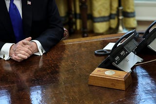 Resolute Desk in the Oval Office. In the center is a wooden box with a red button.