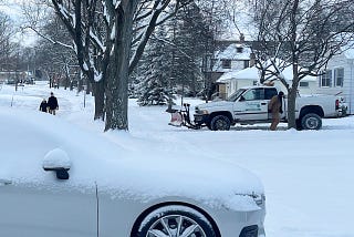 Winter street scene with people walking, snowplow, and a snow covered car