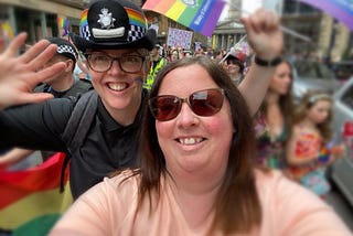 Carlene (in uniform) and her sister posing for a photo at a Pride event, with other people including police officers in the background
