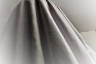 Something that looks like a ghost lurks in a room with white walls.