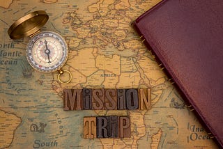A Bible and a compass on top of a map. The letters spell out “Mission Trip”