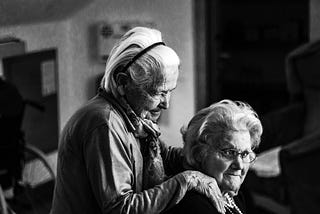 Two old women, one comforting the other.