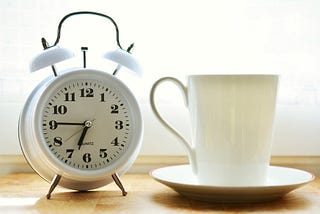 Alarm clock next to a coffee cup