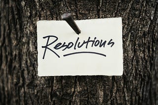 A paper with the word Resolutions, nailed onto a tree