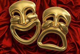 Classic comedy-tragedy theater masks against red curtain fabric.