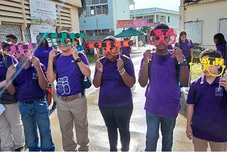 6 students wearing matching uniforms hold colorful glasses labeled with STEAM subjects