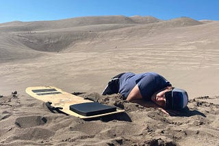 A man laying face down in the sand dunes