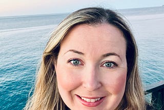 picture of author smiling with the ocean in the background