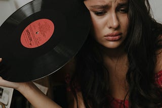 Woman holding vinyl record album, looking sad