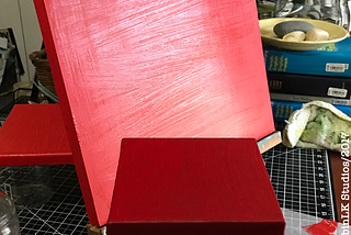 a canvas painted red sits on an easel