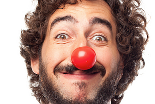 A grinning man wearing a clown’s red nose