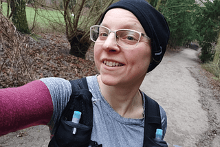 woman runner with black hat and white glasses smiling in the camera