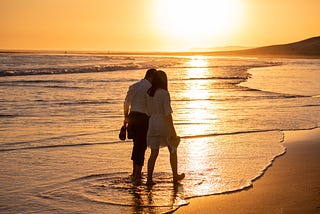 Second chance at love. A couple walk along a beach at sunset on a romantic date