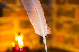 A quill pen in front of a warmly lit but out of focus background
