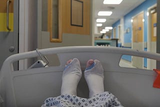 View of my feet in a hospital bed, wearing surgical stockings with one big toe poking out