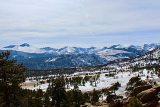 View of mountains and trees with a snow-covered foreground.