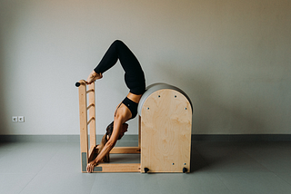 Woman showing the classical Pilates exercise Scorpio on the Ladder Barrel