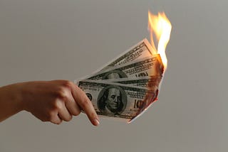 Hand holding burning paper money.