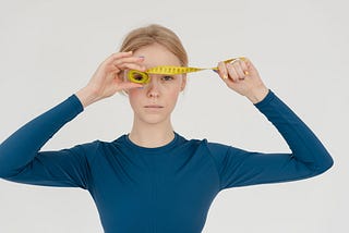 A very thin woman with a serious face and a measuring tape in front of her eyes.