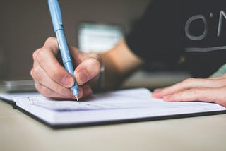 Stock image of a person writing on his note book