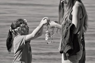 Mum and child making flower chains.