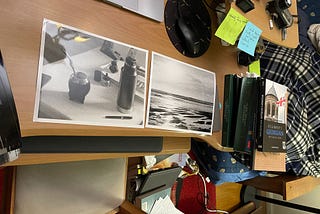 A photo of two black and white prints on a wooden desk made by the author