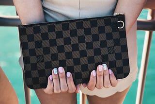 A girl tightly clutching an expensive Louise Vuitton handbag