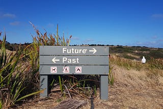 A wayfinding sign of the side of an Australian hiking trail, that reads ‘Future’ with an arrow pointing to the right, and underneath it, ‘Past’ with an arrow pointing to the left.