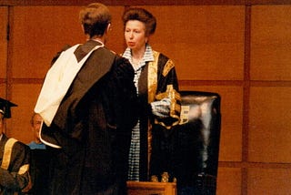 Man in graduation robes being congratulated.