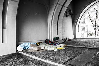 A few sets of blankets and belongings under a bridge