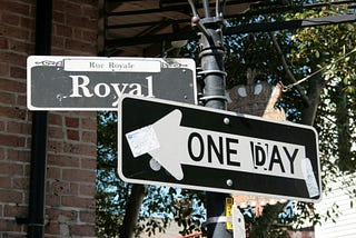 A one-way sign repurposed to say “One day” and pointing left, indicating the road we know we should take but often don’t.