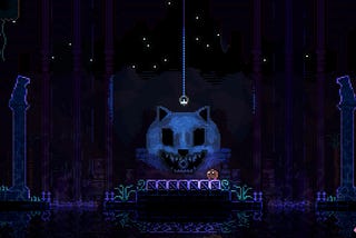 The “blob” standing in front of an eerie-looking wolf’s head statue with a disc in its mouth.