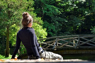 woman in nature looking at a bridge