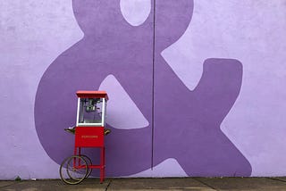 Popcorn cart against a dark purple wall.