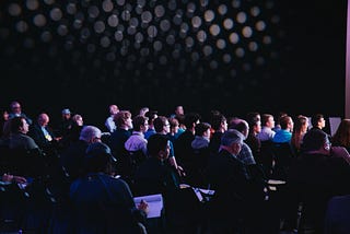 A group of people are sitting on chairs at a conference.