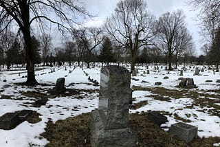 panorama view of granite headstones in snow-covered ground all in rows