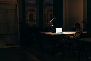 Man working late at his desk, all alone, looking tired. It shows the negative effect of the Hustle Culture.