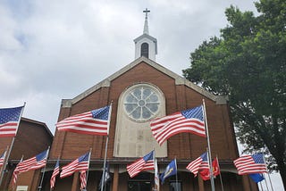 A beautiful church building surrounded by numerous American flags.