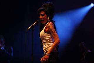 Amy winehouse singing into microphone on stage