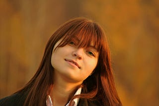 Woman with long red hair gives satisfied look to camera