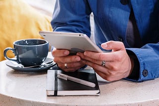 Someone uses a tablet while sitting in a café.