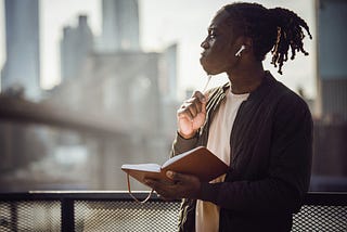 Young African-American man with a notebook and pen thinking hard