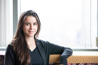 Maria De-Arteaga, McCombs School of Business and Good Systems researcher, stands next to a brightly lit window.