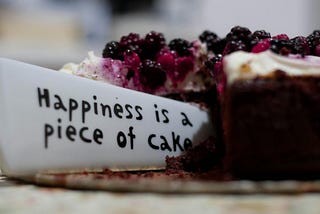 Knife with engravement of “Happiness is a piece of cake” cutting through a cake