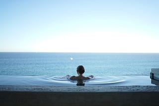 A peaceful woman looking out to the horizon in an infinity pool